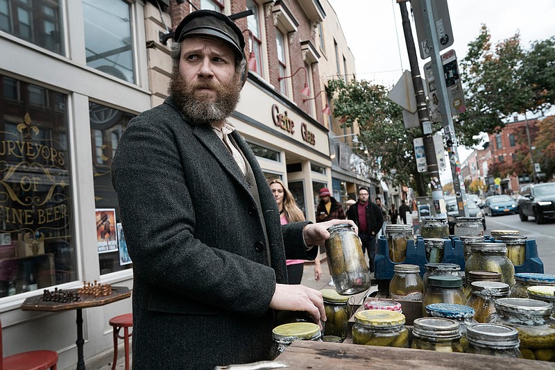 This image released by HBO Max shows Seth Rogen in a scene from "An American Pickle."  Rogen plays dual roles in this film about a man from the 1920s who falls into a vat of pickle juice, wakes up fully preserved 100 years later and gets a chance to know his great-grandson _ a Brooklyn-based app developer. Part "Being There" meets "Kate & Leopold," part Rogen-joint, "American Pickle," has a sweet-heart and a few fun gags that'll make this a pleasant watch when it hits HBO Max Thursday.(Hopper Stone/HBO Max via AP)