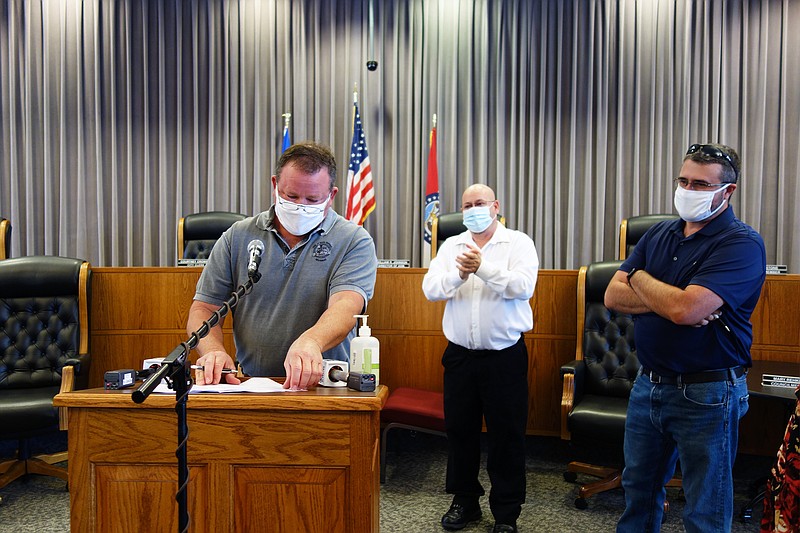 Holts Summit Mayor Landon Oxley, left, signs a joint mask recommendation while Fulton Mayor Lowe Cannell and Kingdom City City Manager Curt Warfield look on.