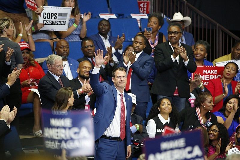 FILE - In this June 20, 2020, file photo, Oklahoma Gov. Kevin Stitt is recognized as President Donald Trump speaks during a campaign rally at the BOK Center, in Tulsa, Okla. Charlie Hannema, spokesperson for Stitt, said Thursday, Aug. 6, 2020, that Stitt, the first governor in the nation to test positive for the coronavirus, was infected when he hugged two friends from Tulsa, on July 10, in Oklahoma City and not connected to the Trump rally. (AP Photo/Sue Ogrocki, File)