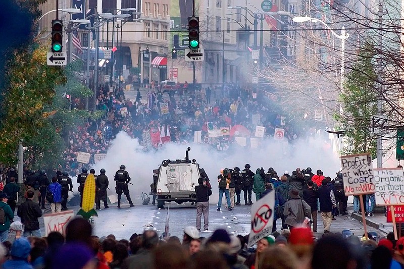 In this Nov. 30, 1999, file photo, Seattle police use tear gas to push back World Trade Organization protesters in downtown Seattle. The Associated Press found that there is no government oversight of the manufacture and use of tear gas. Instead, the industry is left to regulate itself. (AP Photo/Eric Draper, File)