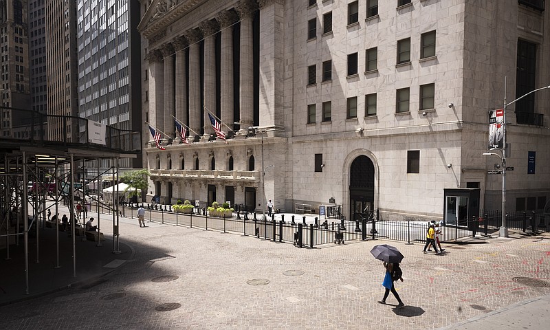 FILE - People pass the New York Stock Exchange, Thursday, July 30, 2020.  Wall Street is stalling on Friday, Aug. 7 as a whirlwind of worries about rising U.S-China tensions and whether Congress can deliver more aid for the economy threaten to halt its big run.(AP Photo/Mark Lennihan)