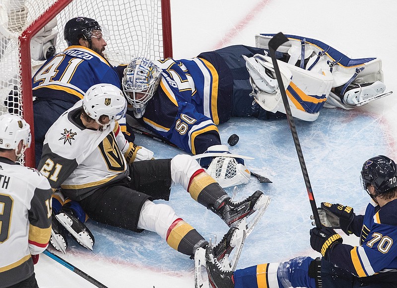 Blues goalie Jordan Binnington makes a save as players crash into the net during the first period of Thursday night's game against the Golden Knights in Edmonton, Alberta.