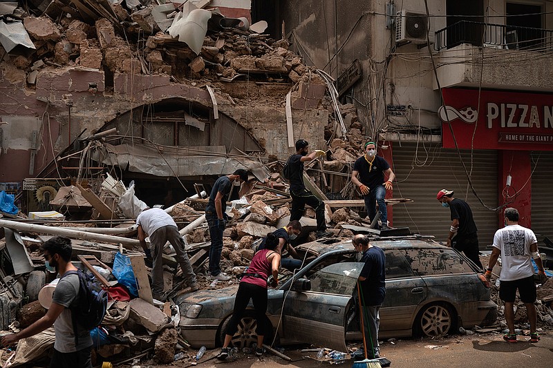 People remove debris from a house damaged by Tuesday's explosion in the seaport of Beirut, Lebanon, Friday, Aug. 7, 2020.  Rescue teams were still searching the rubble of Beirut's port for bodies on Friday, nearly three days after the massive explosion sent a wave of destruction through Lebanon's capital.   (AP Photo/Felipe Dana)