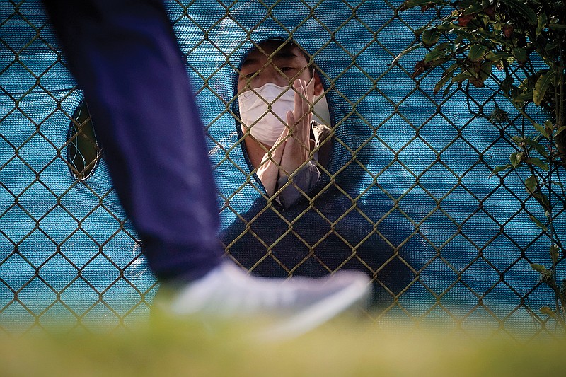 A fan wearing a face mask claps through a hole in the fence as a golfer leaves the 12h tee during Friday's second round of the PGA Championship at TPC Harding Park in San Francisco.