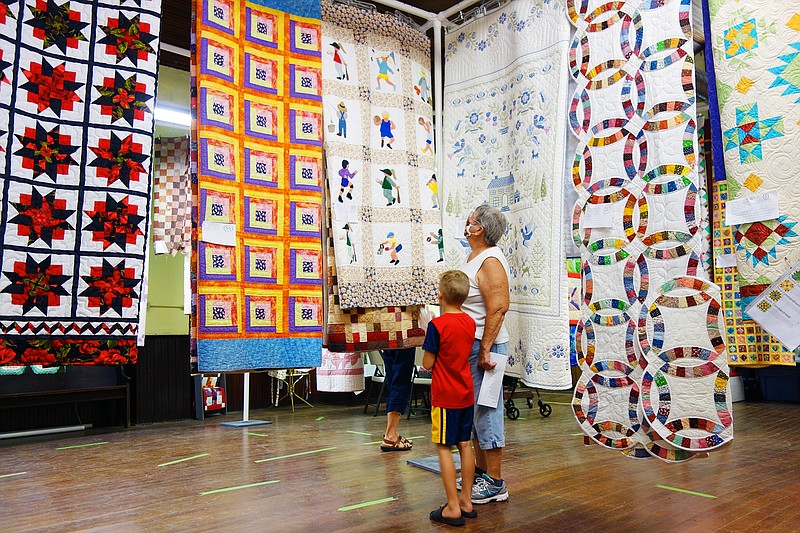 Dot Oliver, right, and 6-year-old Jude Fulkerson of Auxvasse admire quilts at the Williamsburg Quilt Show on Friday. Jude sometimes helps Dot with her quilting, she said. The show, ongoing today, featured more than 60 quilts. 