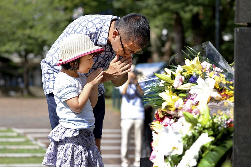 A man and his daughter pray Sunday for the victims of U.S. atomic bombing at the Atomic Bomb Hypocenter Park in Nagasaki, southern Japan. Nagasaki marked the 75th anniversary of the atomic bombing Sunday. (Takuto Kaneko/Kyodo News via AP)