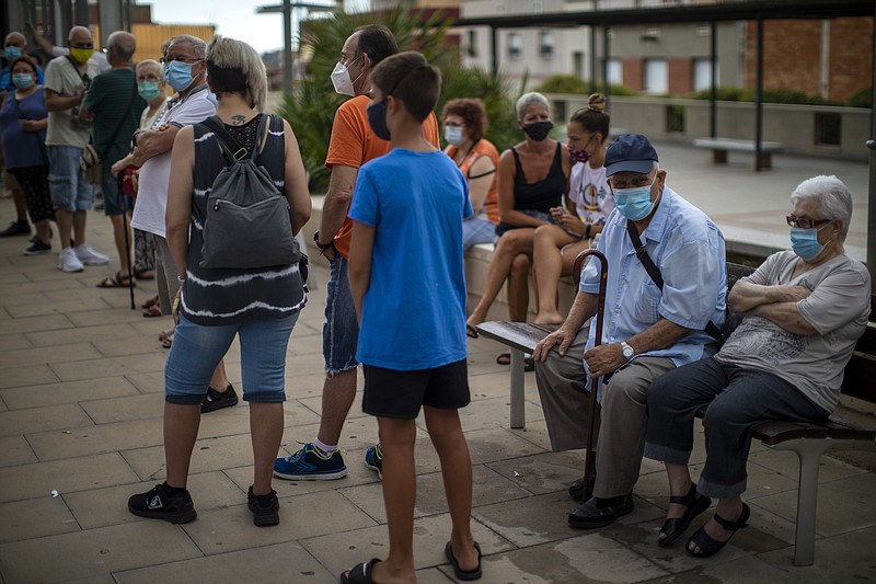 People wearing face masks wait their turn to be called for a PCR test for the COVID-19 outside a local clinic in Santa Coloma de Gramanet in Barcelona, Spain, Tuesday, Aug. 11, 2020. (AP Photo/Emilio Morenatti)