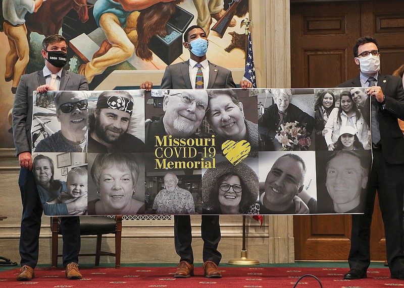 Rep. Ian Mackey, D-St. Louis; Rep. Kevin Windham, D-Hillsdale; and Rep. Matt Sain, D-Kansas City, hold a banner Tuesday in the House Lounge of photos of Missourians who have died from the coronavirus.