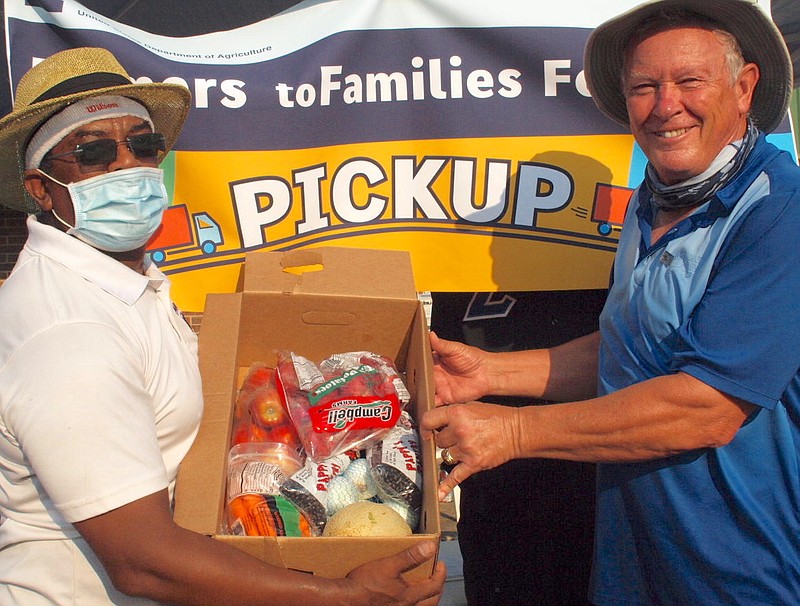 Horace Hodge of Linden, left, and Linden native Edd Hargett, now of College Station, Texas, show the food that is inside the food packets being distributed Saturday through the USDA Farmers to Families Food Box program. The box contains carrots, onions, apples, potatoes, cantaloupe and beans.