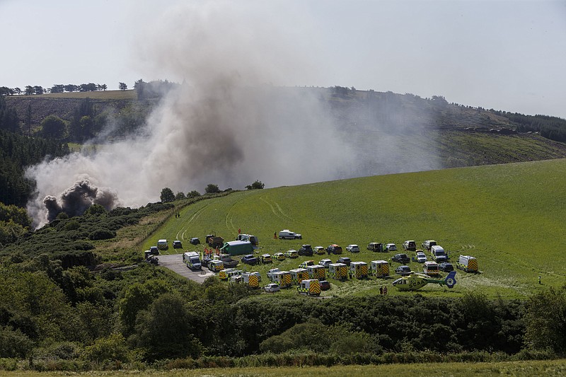 Emergency services attend the scene of a derailed train in Stonehaven, Scotland, Wednesday Aug. 12, 2020. Police and paramedics were responding Wednesday to a train derailment in northeast Scotland, where smoke could be seen rising from the site. Officials said there were reports of serious injuries. The hilly area was hit by storms and flash flooding overnight. (Ross Johnston/Newsline-media via AP)
