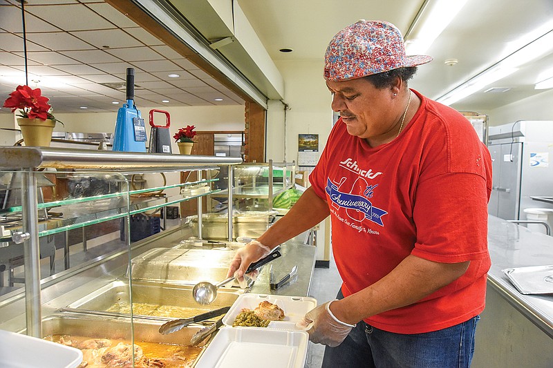 Kenny Shaw fills a to-go container to be carried outside for a client who may pull up at Clarke Senior Nutrition Center for the meal. Shaw works for the program, which receives funding from Aging Best. Individuals do not have to get out of their vehicle; just pull up and wait for a volunteer to carry out the prepared food.