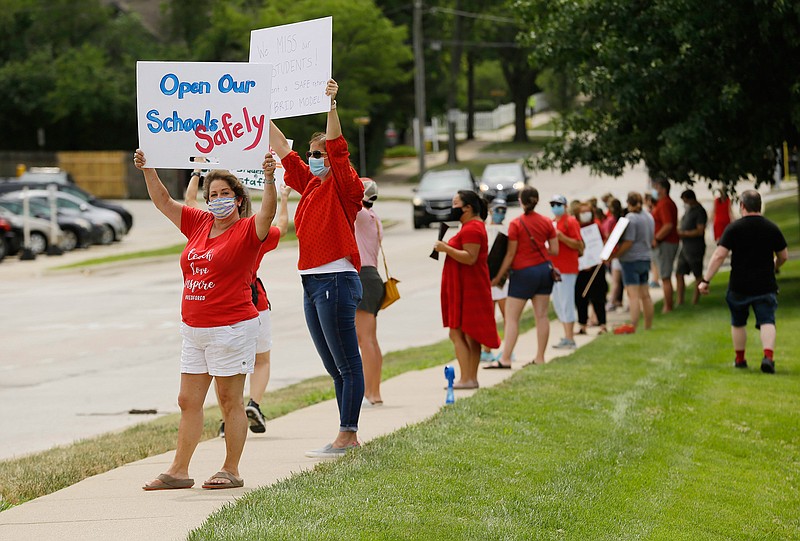 Sara Havel, left, co-president of the teacher's union in District 181, holds a sign along with dozens of other teachers outside of the district building on July 30, 2020, in Clarendon Hills, Ill. Teachers are asking the district to change its plan for a full-time return to school this fall. Promoting the idea of continuing with online learning in the fall, the teachers argue that it's still not safe to go back to school. (Stacey Wescott/Chicago Tribune/TNS)