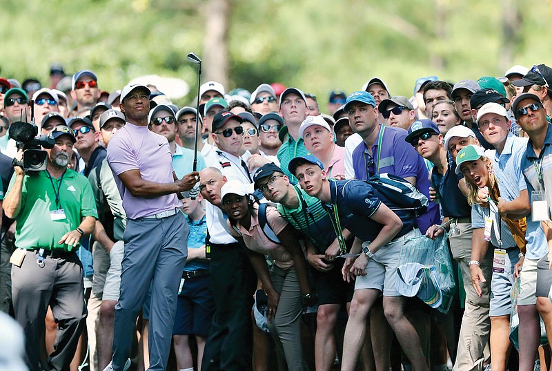 In this April 13, 2019, file photo, Tiger Woods hits from the gallery along the 11th fairway during the third round of the Masters at Augusta National in Augusta, Ga.