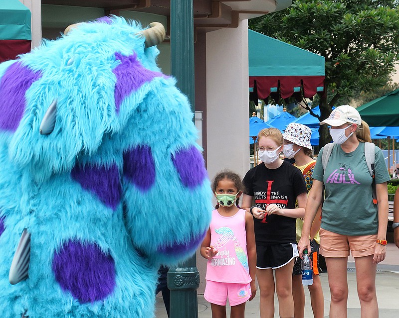 Guests wave to Sulley of Monsters, Inc. during a pop-up appearance of Pixar characters at Disney's Hollywood Studios at Walt Disney World, on the second day of the park's re-opening on July 16. (Joe Burbank/Orlando Sentinel/TNS)