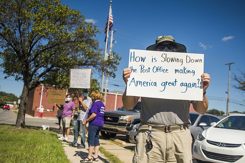 Eric Severson holds a sign as a few dozen people gather in front of the United States Post Office on Rodd St. to protest recent changes to the U.S. Postal Service under new Postmaster General Louis DeJoy Tuesday, Aug. 11, 2020 in Midland, Mich. (Katy Kildee/Midland Daily News via AP)