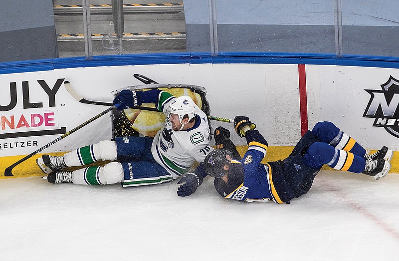 Tanner Pearson of the Canucks and Carl Gunnarsson of the Blues crash into the boards Wednesday night during the third period in Game 1 of a first-round playoff series in Edmonton, Alberta.