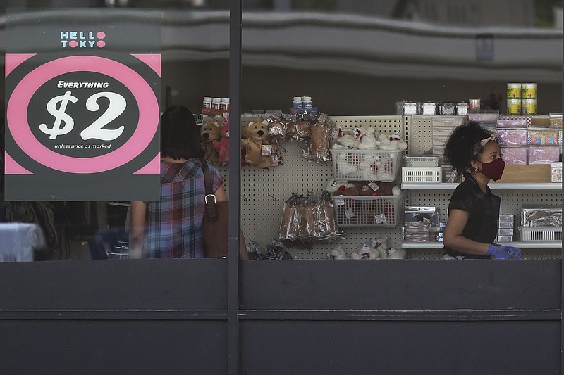 FILE - In this June 25, 2020 file photo, a price sign is displayed at a retail store as a store employee wears a mask while working in Niles, Ill.   Small businesses are in limbo again as the coronavirus outbreak rages and the government’s $659 billion relief program draws to a close. Companies still struggling with sharply reduced revenue are wondering if Congress will give them a second chance at the Paycheck Protection Program, which ends Friday, Aug. 7,  after giving out 5.1 million loans worth $523 billion.  (AP Photo/Nam Y. Huh, File)