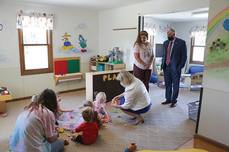 AUGUST 2020 FILE: Show Me Child Care Center founder and Director Julie Schmitz and Gov. Mike Parson watch as first lady Teresa Parson plays with children at the center Tuesday in Jefferson City. 