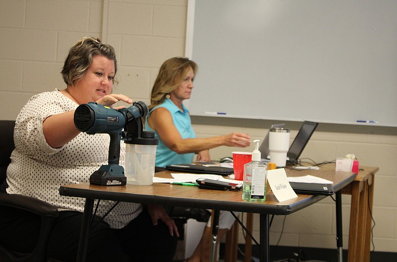 Superintendent Sarah Wisdom demonstrates a disinfectant spray-tool.