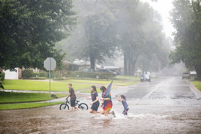 Children play in the rainwater Thursday on Potomac Avenue in Texarkana, Texas, after the area got several hours of rain as Hurricane Laura moved inland through the region.
