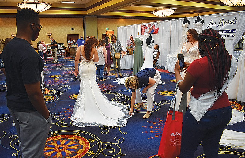 Daniel White, left, and fiancée Danisha Hogue look at a dress worn by Cate Gladbach, a model for Ana Marie's Bridal, during Sunday's Fall Bridal Spectacular at Capitol Plaza Hotel.