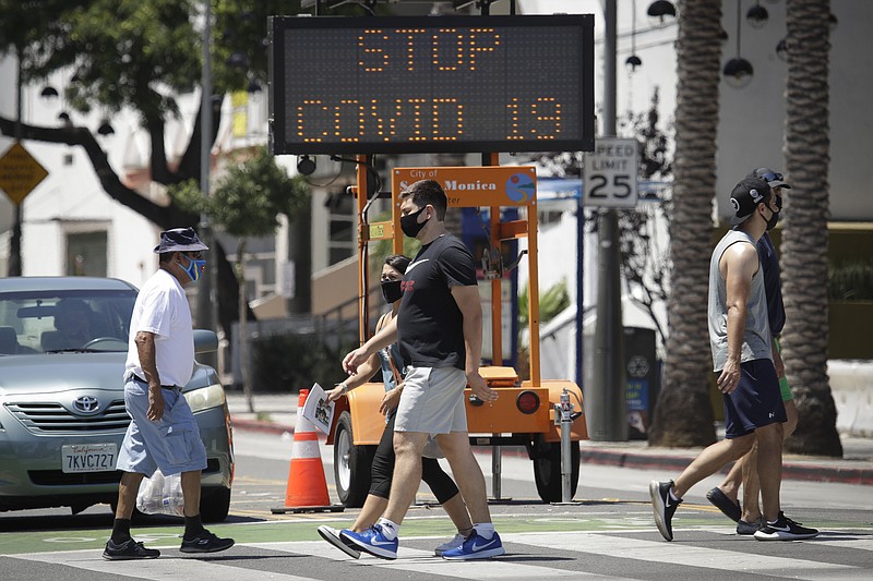 FILE - In this July 12, 2020, file photo, pedestrians wear masks as they cross a street amid the coronavirus pandemic in Santa Monica, Calif. The torrid coronavirus summer across the Sun Belt is easing after two disastrous months that brought more than 35,000 deaths. (AP Photo/Marcio Jose Sanchez, File)
