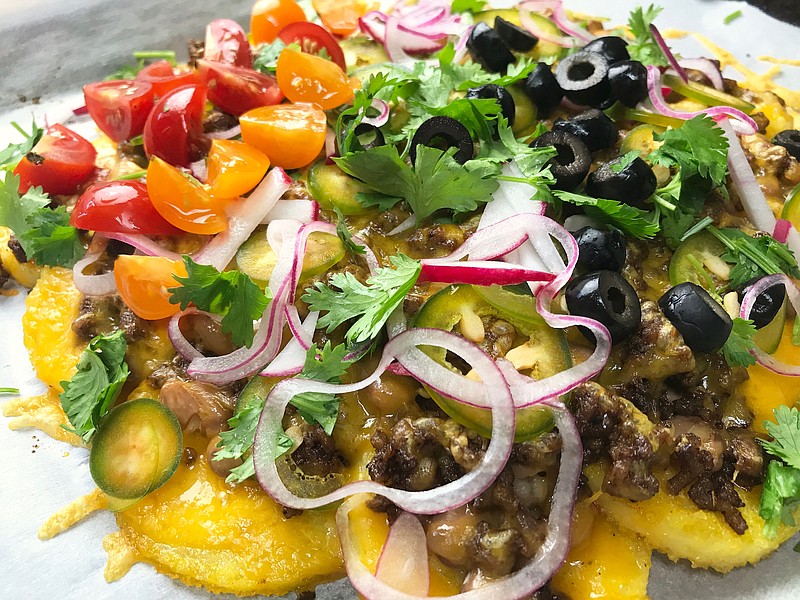 Polenta Nachos, or "polentchos",  are rounds of pan-fried polenta topped with seasoned beef, beans, cheese, jalapenos, radishes, olives, tomatoes, pickled onion and cilantro. (Arkansas Democrat-Gazette/Kelly Brant) Aug. 7 2020
