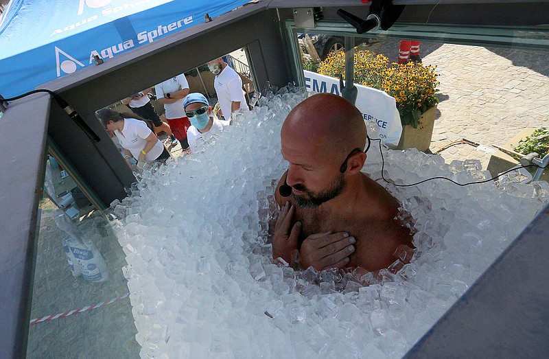 Austrian ice swimmer Josef Koerbel is standing in a glass cabin filled with ice try to break the world record for a human to stay side an ice box in Melk, Saturday, Sept. 5, 2020. (AP Photo/Ronald Zak)