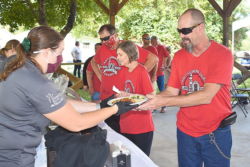 At left, Makayla Stubinger, of Reinhardt Circle catering, hands a fried chicken dinner to Jimmy Crawford during Trinity Evangelical Lutheran Church's 125th anniversary celebration Sunday.