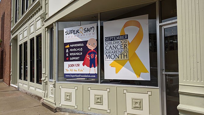 Window clings focused on childhood cancer awareness month decorate a storefront on Fifth Street in downtown Fulton. Though COVID-19 has made in-person events complicated, Super Sam Foundation still has fundraising plans for September.