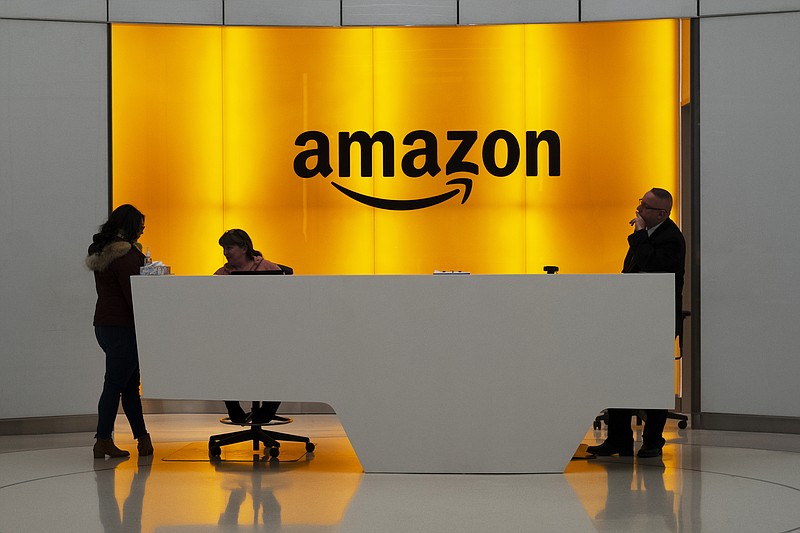 FILE - In this Feb. 14, 2019 file photo, people stand in the lobby for Amazon offices in New York. While other companies are shrinking, Amazon is growing. The company said Wednesday, Sept. 9, 2020, that it is seeking to hire 33,000 people for corporate and tech roles in the next few months (AP Photo/Mark Lennihan, File)