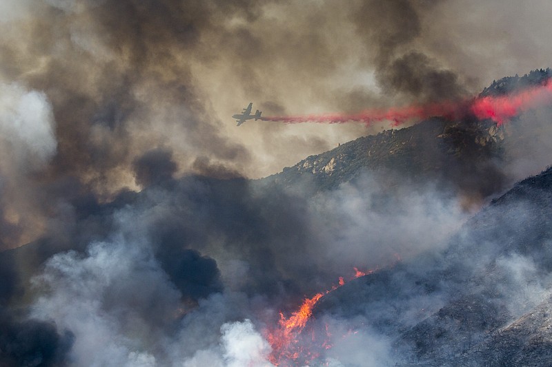 FILE - In this Saturday, Sept. 5, 2020 file photo, an air tanker drops fire retardant on a hillside wildfire in Yucaipa, Calif. A hotter world is getting closer to passing a temperature limit set by global leaders five years ago and may exceed it in the next decade or so, according to a new United Nations report released on Wednesday, Sept. 9, 2020. (AP Photo/Ringo H.W. Chiu)