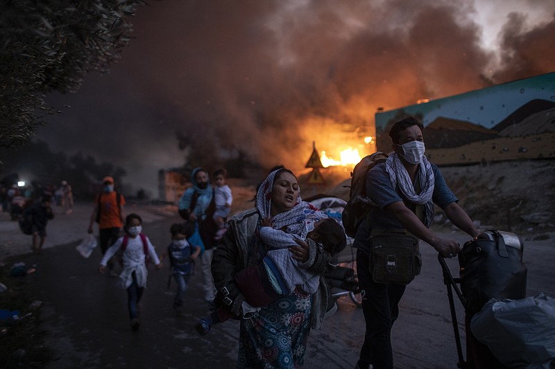 Migrants flee from the Moria refugee camp during a second fire, on the northeastern Aegean island of Lesbos, Greece, on Wednesday, Sept. 9, 2020. Fire struck again Wednesday night in Greece's notoriously overcrowded refugee camp on the island of Lesbos, a day after a blaze swept through it and left thousands in need of emergency shelter. The fires caused no injuries, but they renewed criticism of Europe's migration policy. (AP Photo/Petros Giannakouris)