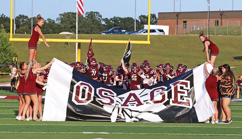 The School of the Osage Indians run onto the field prior to this year's season opener against Fulton at Osage Beach.