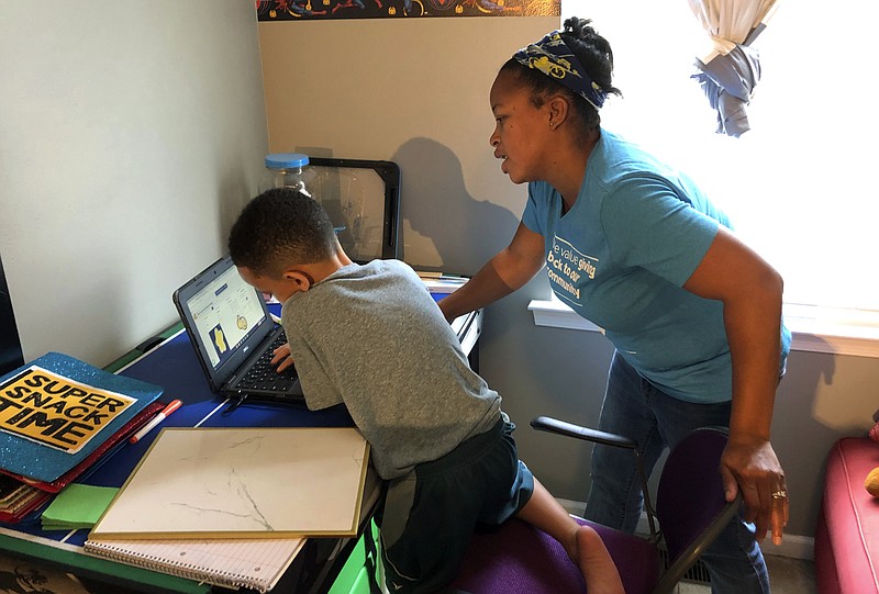 Tiffany Shelton helps her 7-year-old son, P.J. Shelton, a second-grader, during an online class at their home in Norristown, Pa., on Thursday, Sept. 3, 2020. Norristown Area School District plans to offer online-only instruction through at least January 2021. (AP Photo/Michael Rubinkam)