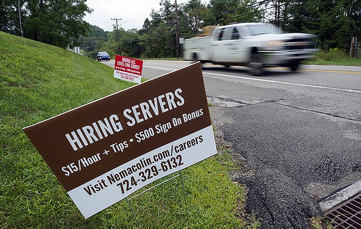 FILE - In this Wednesday, Sept. 2, 2020, file photo help wanted signs for servers and cooks at Nemacolin Woodlands Resort and Spa are displayed along route 40 at the entrance to the resort in Farmington, Pa. U.S. employers advertised more jobs but hired fewer workers in July, sending mixed signals about a job market in the wake of the coronavirus outbreak. The Labor Department said Wednesday, Sept. 9, 2020, that the number of U.S. job postings on the last day of July rose to 6.6 million from 6 million at the end of June. (AP Photo/Gene J. Puskar, File)