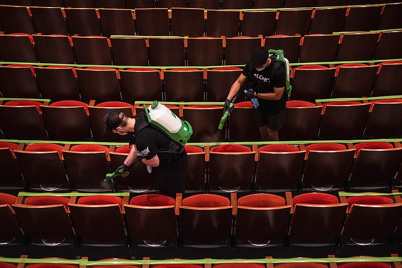 Two Zoono employees spray disinfectant on theater seats in the Wagner Noel Performing Arts Center on Thursday, Sept. 10, 2020, in Odessa, Texas, in preparation for the reopening of the venue for its first performance on Sept. 15. (Eli Hartman/Odessa American via AP)