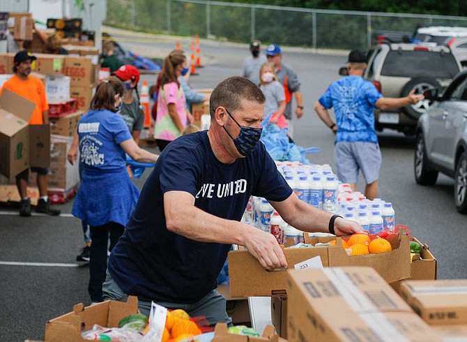 Jason Schwartz puts out boxes of fresh produce to load into waiting cars during a mobile food pantry Saturday morning, Sept. 12, 2020, in the parking lot of Helias Catholic High School's athletic complex. This was the first time the Food Bank for Central & Northeast Missouri brought two trucks of food instead of one. Members of Hawthorn Bank made up the bulk of Saturday's volunteers.