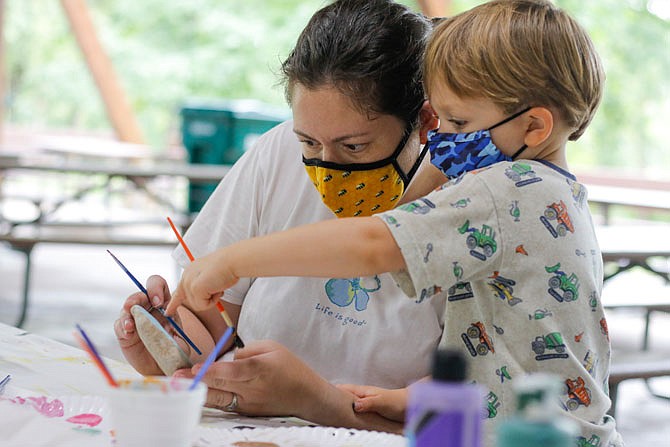 Kristy Manning listens to her son, Ephram Manning-Treece, 3, as he points out the clouds Saturday on her painted rock during JC Rocks' rock painting event, called Rockfest, at Memorial Park. The rocks will be hidden in various parks, neighborhoods and outdoor spaces to spread a little artistic joy to those who find them.