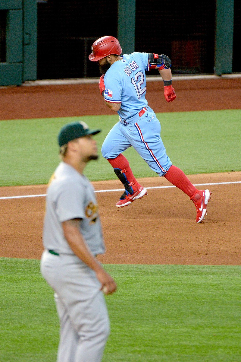 Texas Rangers' Rougned Odor rounds the bases as Oakland Athletics starting pitcher Frankie Montas looks at the scoreboard Sunday in Arlington, Texas. Odor hit a three-run home run in the sixth inning.
