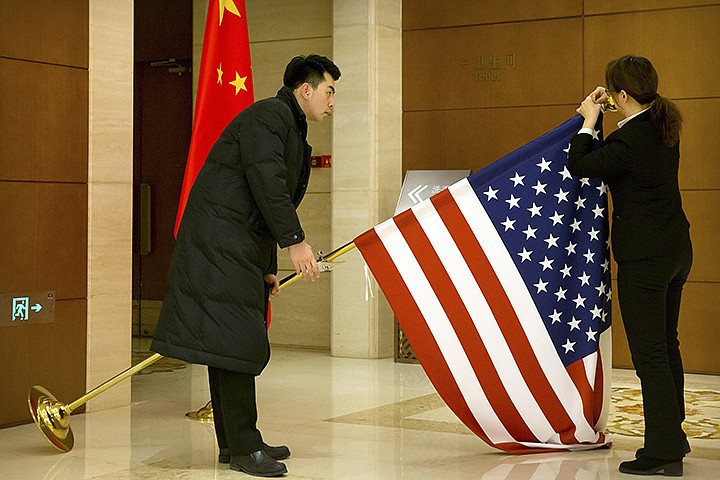 In this Feb. 14, 2019, file photo, Chinese staffers adjust a U.S. flag before the opening session of trade negotiations between U.S. and Chinese trade representatives at the Diaoyutai State Guesthouse in Beijing. China is delaying the renewal of press cards for at least five journalists working at four U.S. media outlets, an organization of foreign correspondents said Monday, Sept. 7, 2020 making them vulnerable to expulsion in apparent retribution for Washington's targeting of Chinese reporters working in the United States. (AP Photo/Mark Schiefelbein, Pool, File)