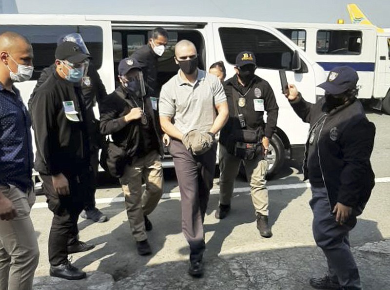 In this photo provided by the Philippines' Bureau of Immigration Public Information Office, (PIO), U.S. Marine Lance Cpl. Joseph Scott Pemberton, center, is escorted as he arrives at the airport before boarding a U.S. military plane in Manila, Philippines, Sunday, Sept. 13, 2020. Pemberton, a U.S. Marine convicted of killing a Filipino transgender woman, was deported Sunday after a presidential pardon cut short his detention in a case that renewed outrage over a pact governing American military presence in the Philippines. (Bureau of Immigration PIO via AP)