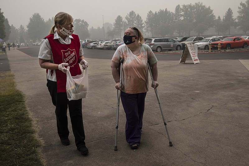 Mary Thomson, left, from Phoenix gets assistance from Salvation Army officer Tawnya Stumpf at the evacuation center set up at the Jackson County Fairgrounds on Saturday, Sept. 12, 2020 in Central Point, Ore. They lost their home to the destructive wildfires devastating the region. (AP Photo/Paula Bronstein)