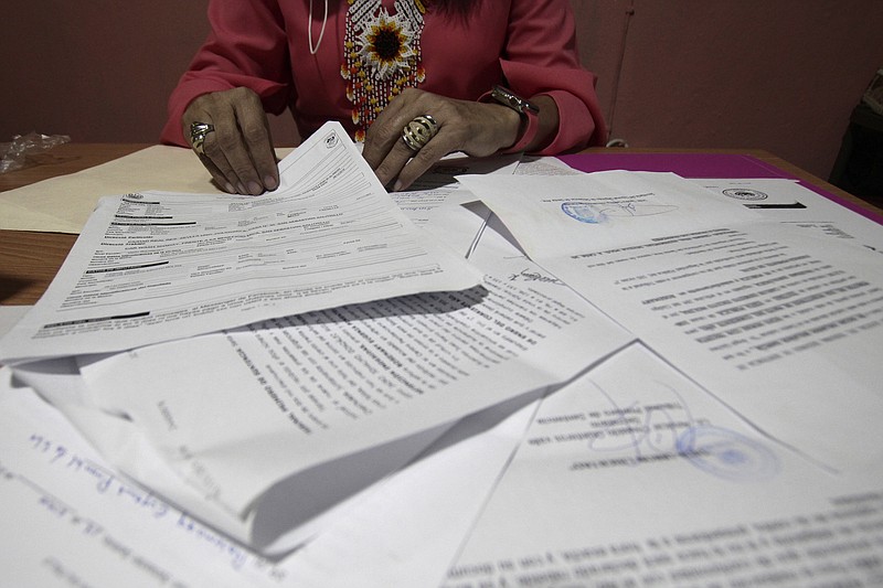 A Salvadoran businesswoman, who is one of the applicants of a small refugee program that was shut down by President Donald Trump, shows documents of the many times she has reported robberies and extortions, in Santa Ana, El Salvador, Saturday, Aug. 22, 2020. She said she was terrified when she began receiving death threats in 2013. Men with tattoos would come to a car wash she used to own to demand "monthly compensation" for letting her operate. She says she has received many threats since — through calls, text messages and social media. (AP Photo/Salvador Melendez)