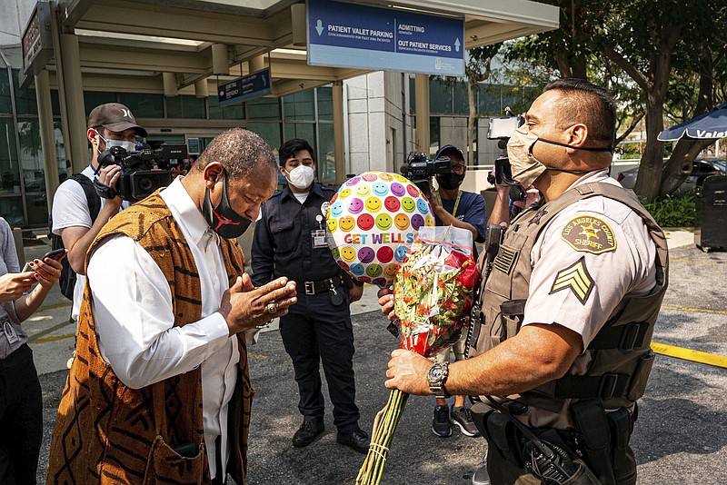 Najee Ali, of Project Islamic Hope, presents Sgt. Larry Villareal, of the Los Angeles County Sheriff Dept., flowers for deputies recovering at St. Francis Medical Center in Lynwood, Calif., Monday, Sept. 14, 2020. The two deputies were shot Saturday while in their patrol vehicle in an ambush-style attack. Ali was especially troubled by reports that protesters were at the hospital chanting "we hope they die" while the officers were fighting for their lives. (David Crane/The Orange County Register via AP)