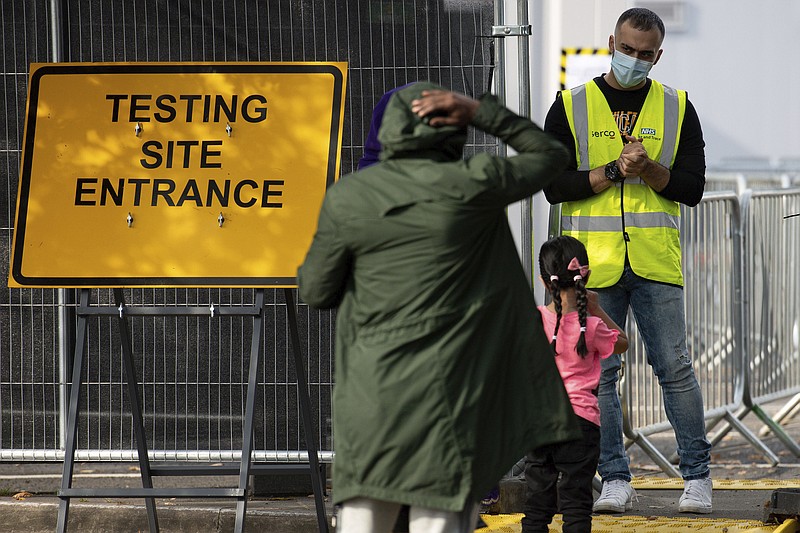 People talk to staff at the entrance to a coronavirus testing facility in Sutton Coldfield, England, Tuesday Sept. 13, 2020.  New measures are in place banning people from different homes from meeting together in some English cities, in response to a local rocketing coronavirus infection rate, although there is widespread criticism over the availability of testing facilities. (Jacob King/PA via AP)