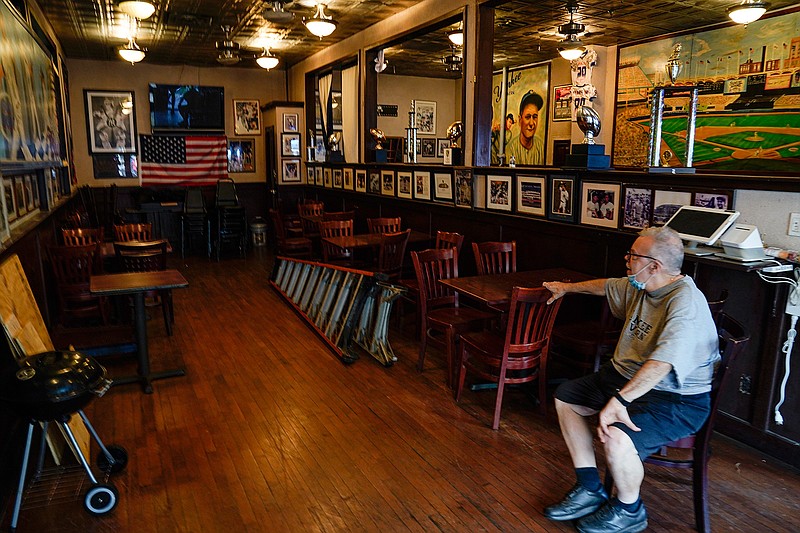 Joe Bastone, owner of Yankee Tavern, sits in an empty dining room before the Boston Red Sox played the New York Yankees on Friday, Aug. 14, 2020, in New York. The coronavirus pandemic has been especially hard on businesses that rely on ballpark traffic, eliminating crowds at major league games, and leading to rules that limit the amount of people they can have inside their doors at the same time. (AP Photo/Frank Franklin II)