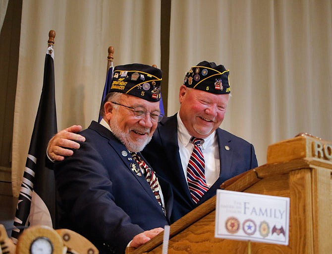 Past American Legion Post 5 Commander and current Judge Advocate Charlie Goodin, left, laughs and embraces incoming Commander Gary Kempker as he officially installs Kempker as commander of the post at Tuesday's special ceremony.