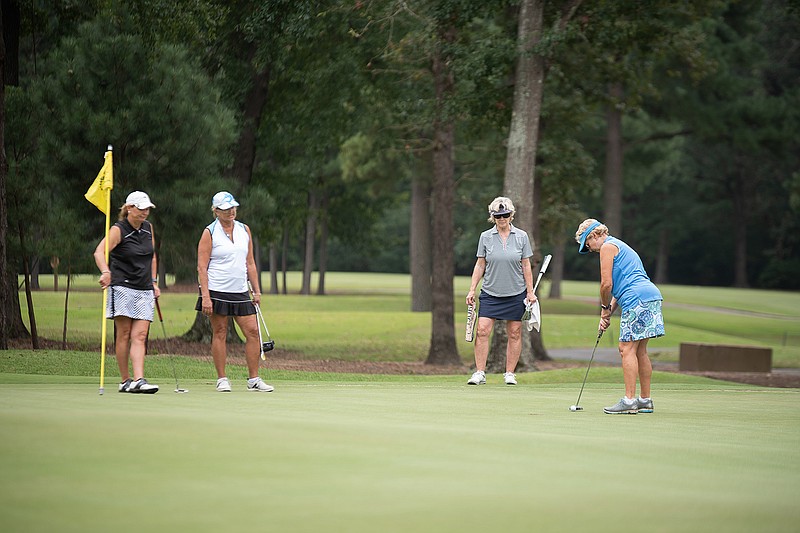 Suzanne Tinsley and Susan Wright, left, and Judy Brady, middle, watch as Mary Anne Knipe prepares to putt the ball into the hole at the Twice as Nice Ladies Invitational golf tournament on Wednesday at Texarkana Country Club. The tournament features 58 teams with a 9 a.m. shotgun start each day.