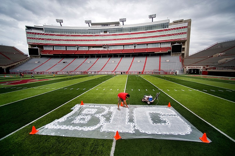 In this Thursday, Oct. 6, 2011 file photo, turf manager Jared Hertzel touches up the newly-painted Big Ten conference logo on the football field at Memorial Stadium in Lincoln, Neb. Big Ten is going to give fall football a shot after all. Less than five weeks after pushing football and other fall sports to spring in the name of player safety during the pandemic, the conference changed course Wednesday and said it plans to begin its season the weekend of Oct. 23-24. (Jacob Hannah/Lincoln Journal Star via AP, File)